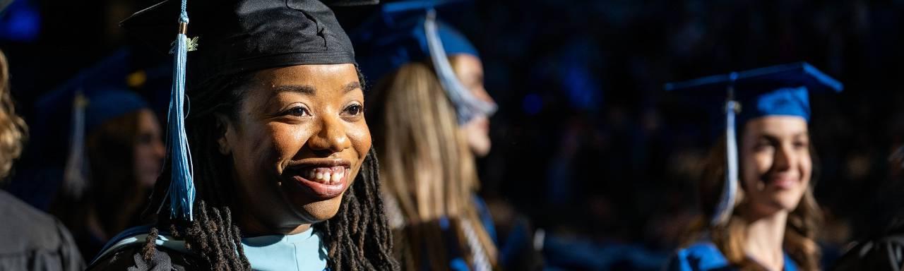 A GVSU student in cap and gown walks toward the stage during commencement